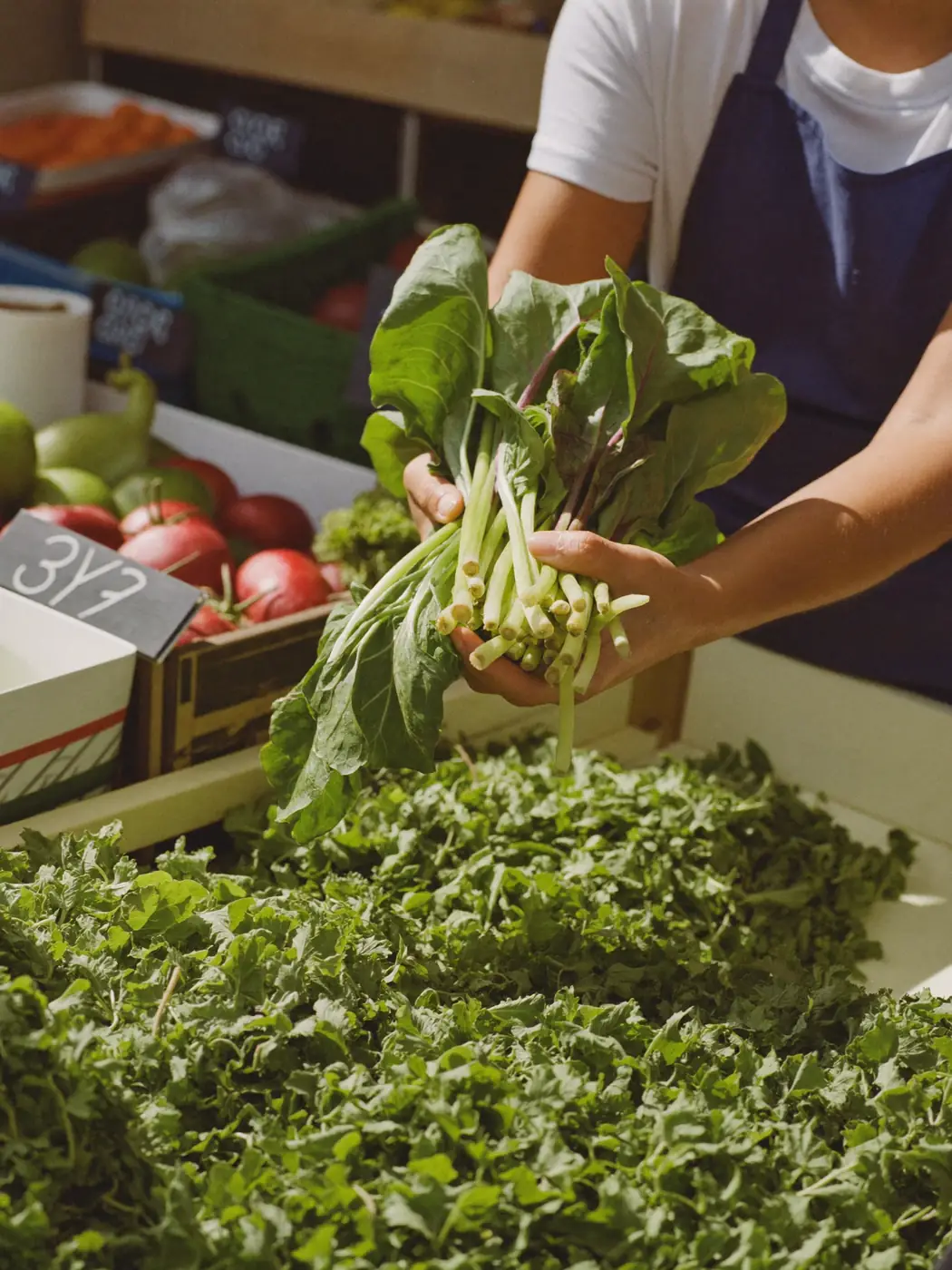 Crates of leafy greens and citrus stacked high at a stall