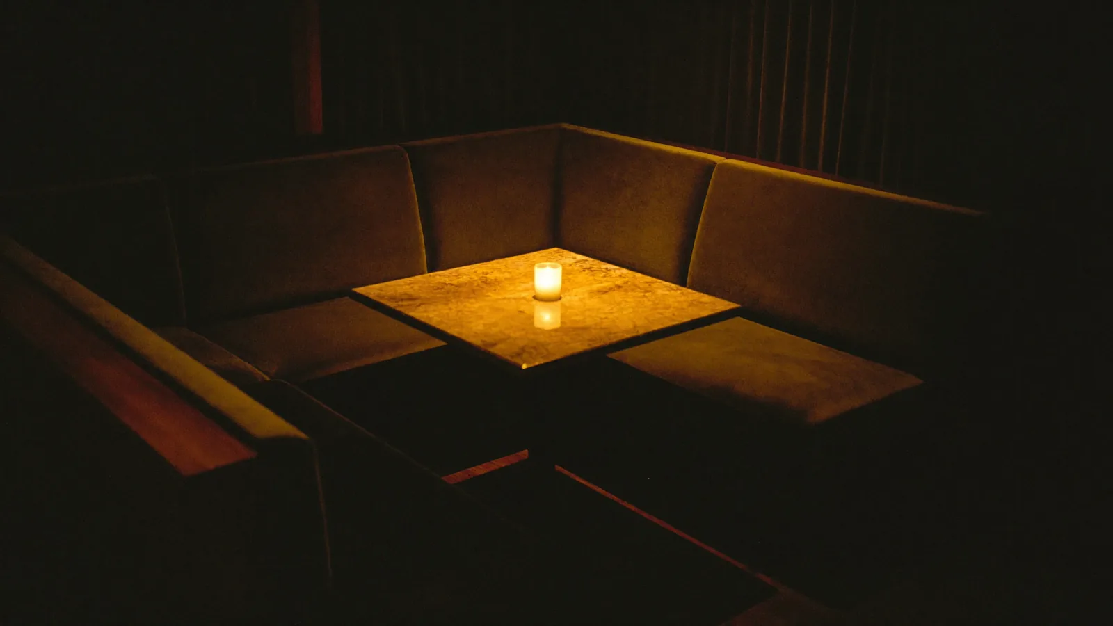 A single amber cocktail glowing on the dark counter